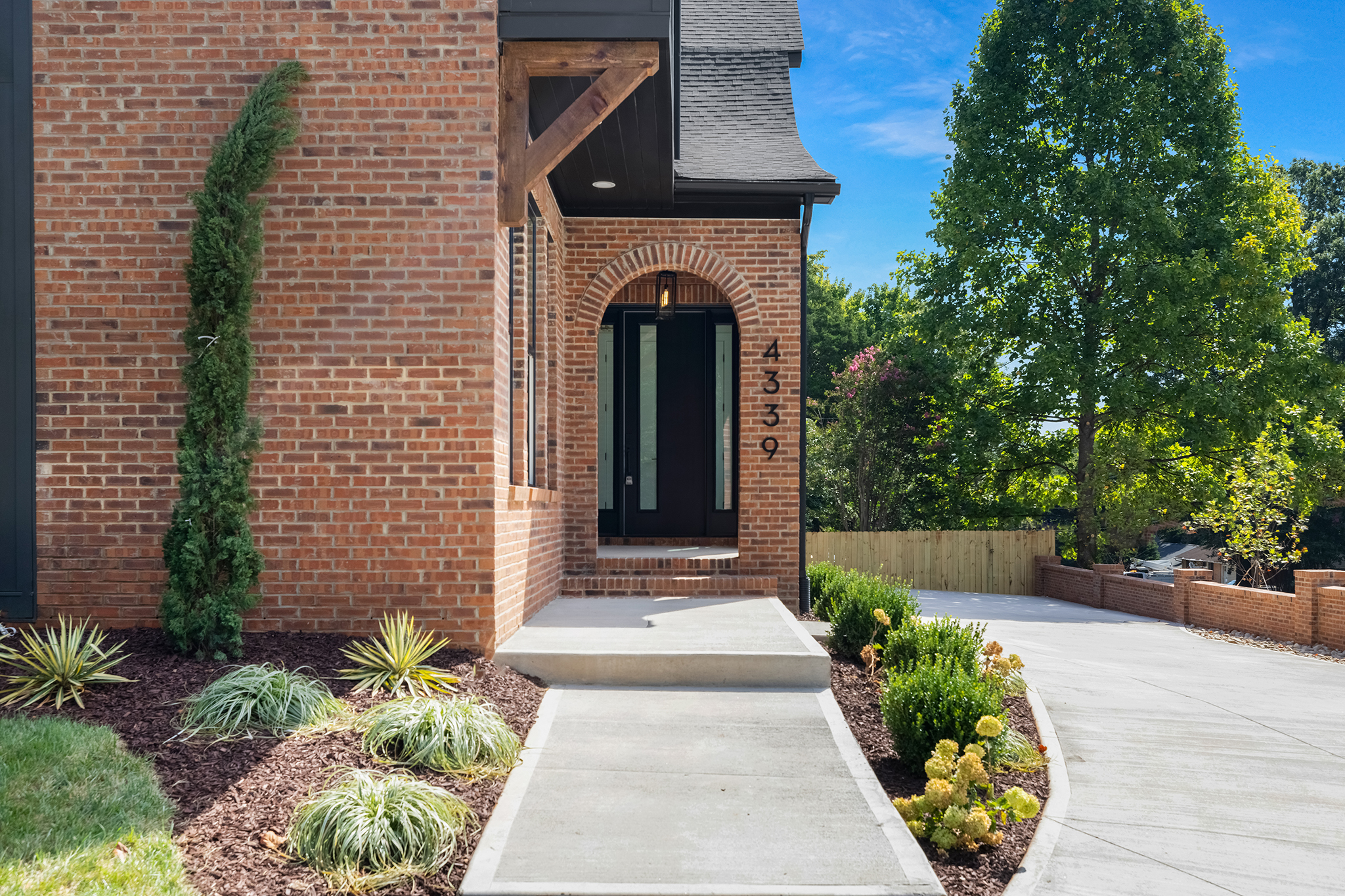 Brick entry with an arched front door and a landscaped walkway