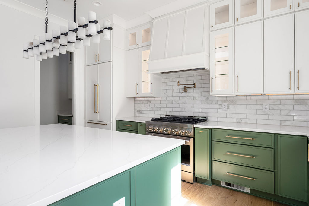 Kitchen with green cabinetry, white countertops and a tile backsplash