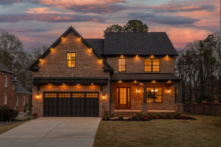 Two-story shingle and stone exterior lit at twilight