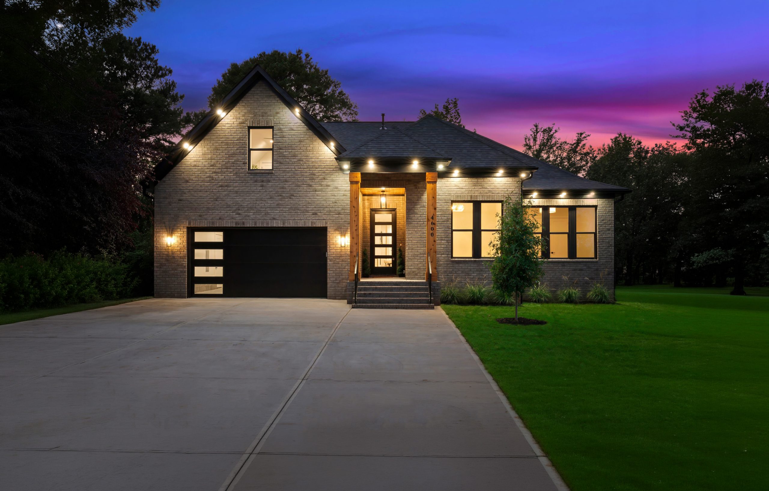 Two-story new construction home with illuminated windows and covered entry at dusk