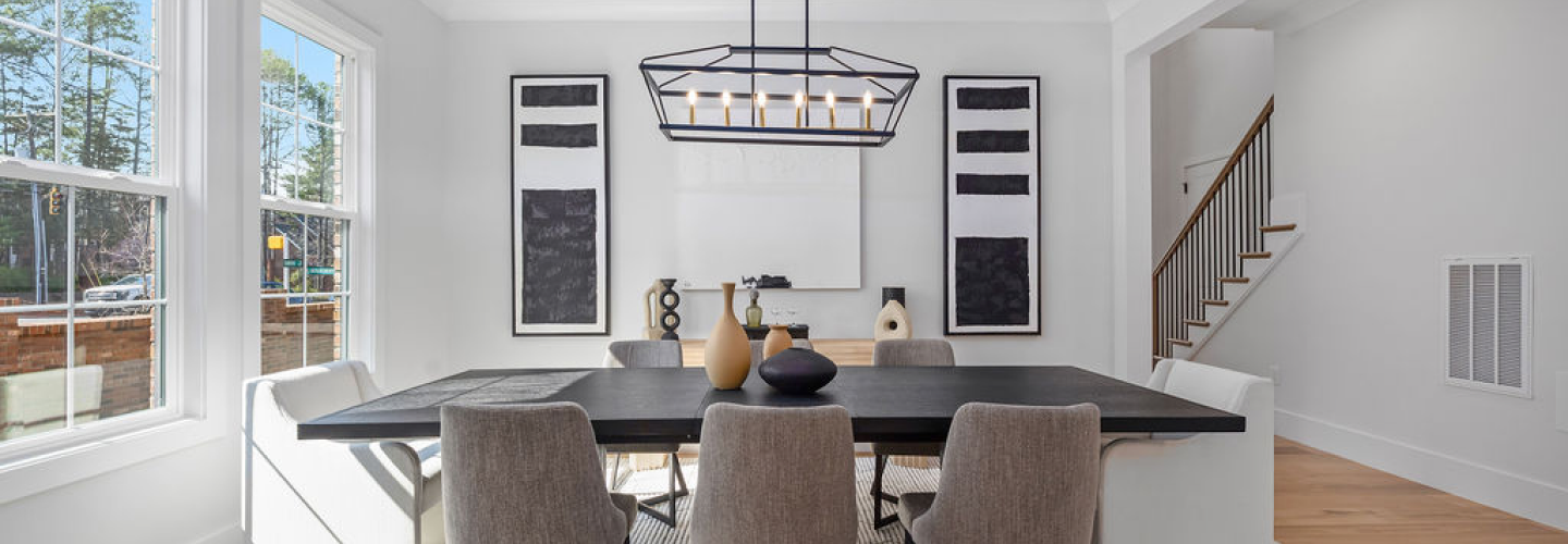 Staged dining room with a dark wood table, upholstered chairs, and a black metal chandelier in a Northway Homes interior