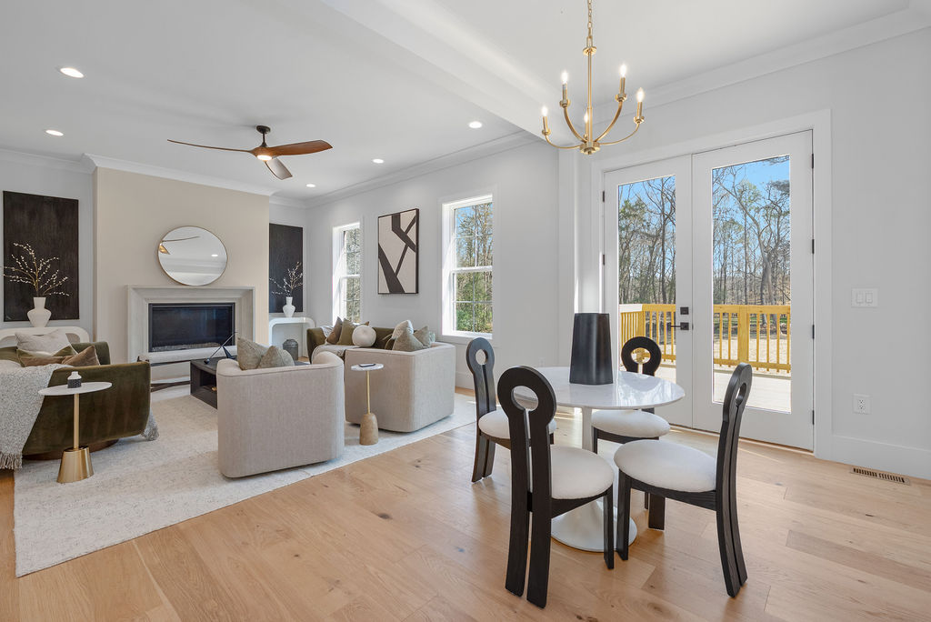 Open-concept living and dining room with a round table, black metal chandelier, and French doors to a deck